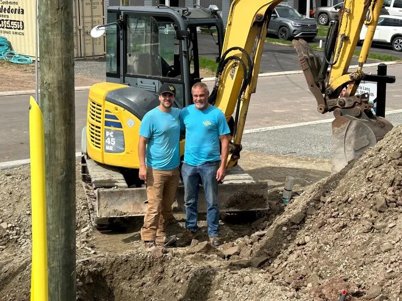 RJS crew standing in front of an excavator beside a trench for an underground service
