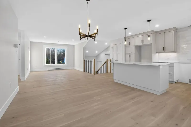 Finished bright open-concept kitchen and living area with pot lights and pendant lights