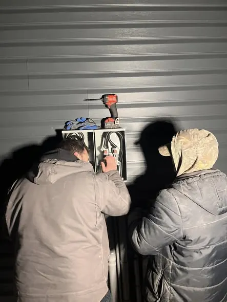 Two RJS electricians working on an electrical panel at night