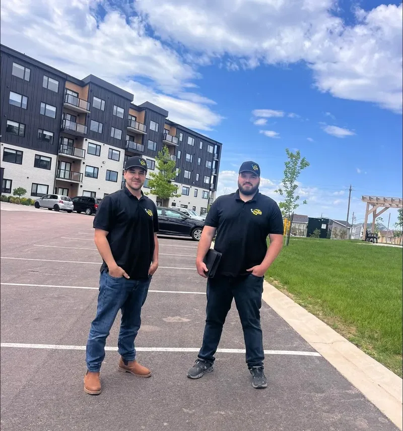 Rejean Richard and Shawn Clements of RJS Electric in RJS shirts and caps in front of an apartment building