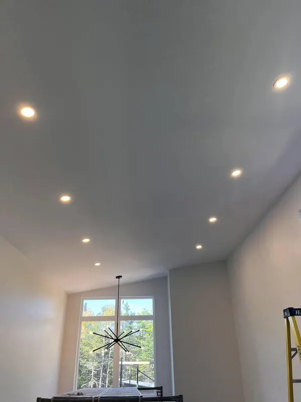 Vaulted ceiling with recessed pot lights and a modern chandelier