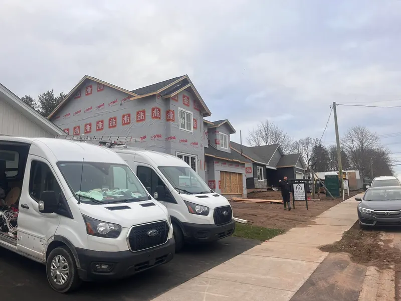 Two white Ford Transit RJS work vans on a street of new-build homes