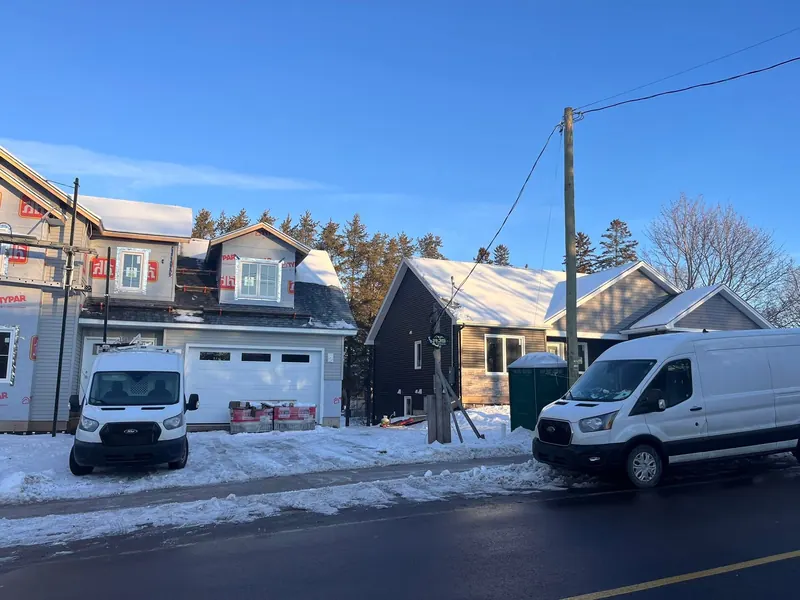 White RJS Electric work vans parked at new homes in winter